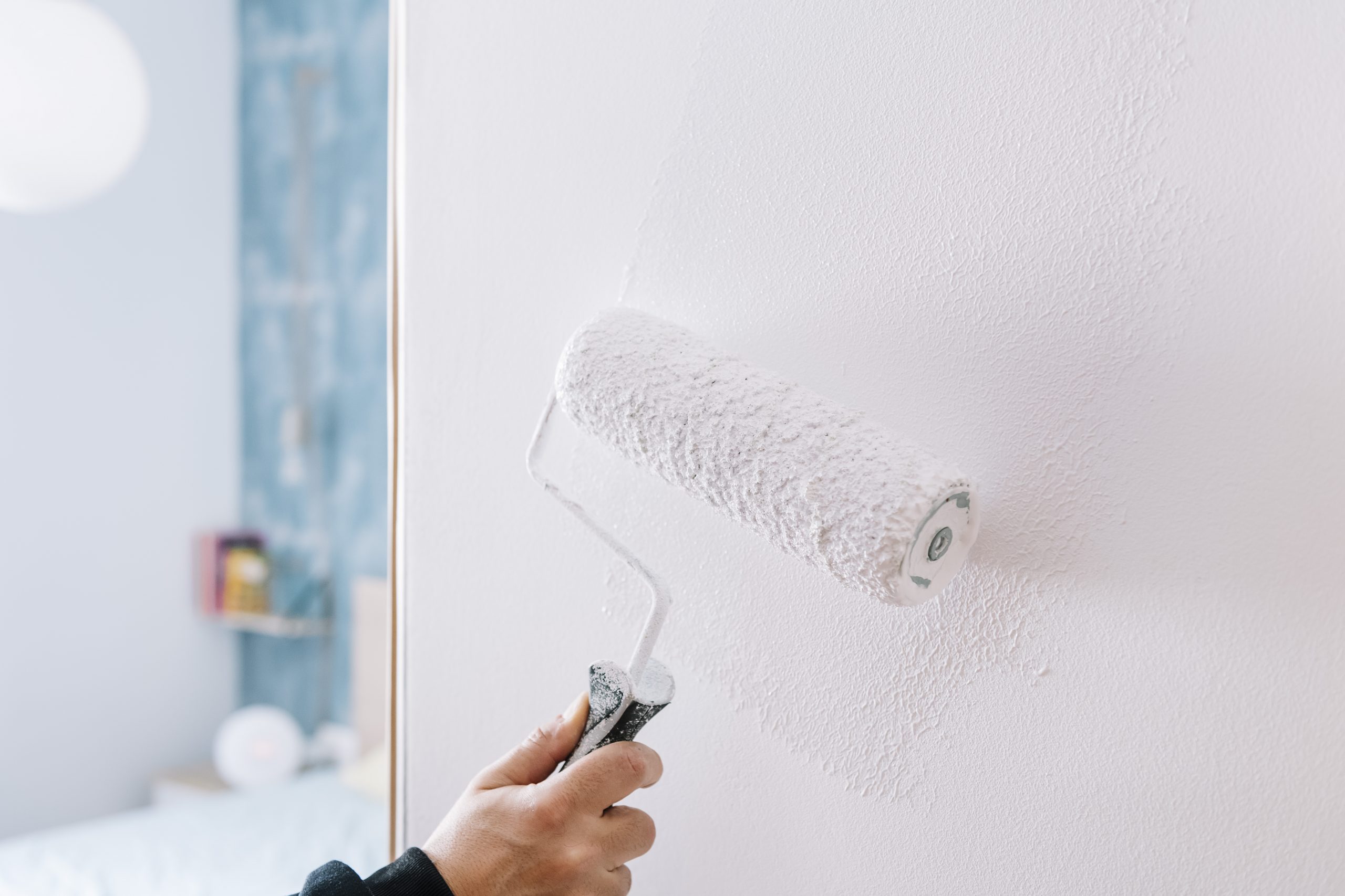 painting a wall in white with a roller